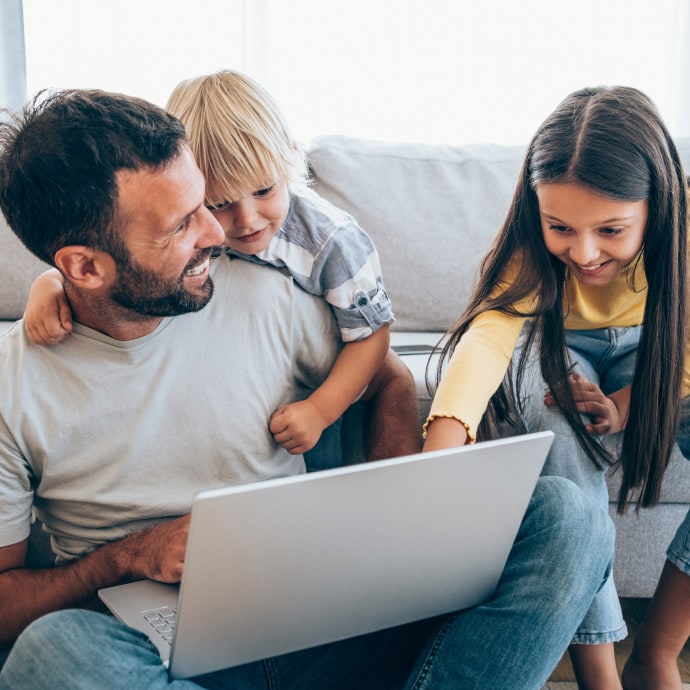 Father with two kids smiling with laptop - Norton 360 Deluxe
