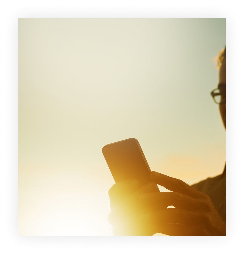 Norton Money: Man checking his cell phone in sunset